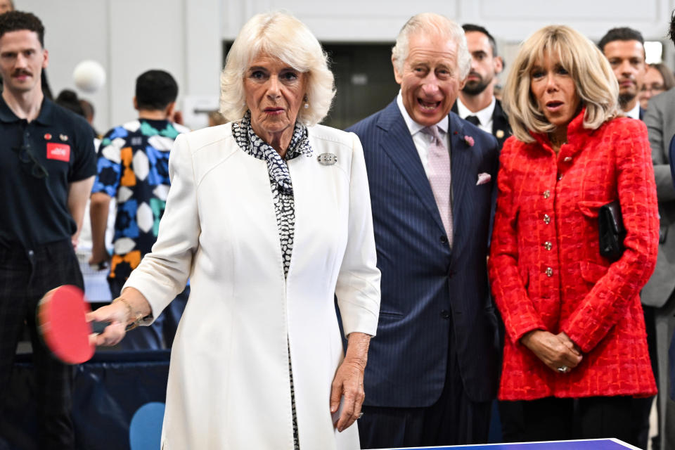 Britain's Queen Camilla plays table tennis as Britain's King Charles III, French President Emmanuel Macron's wife Brigitte Macron, look on during visit to a gymnasium, Thursday, Sept. 21, 2023 in Saint-Denis, outside Paris. (Bertrand Guay, Pool via AP)