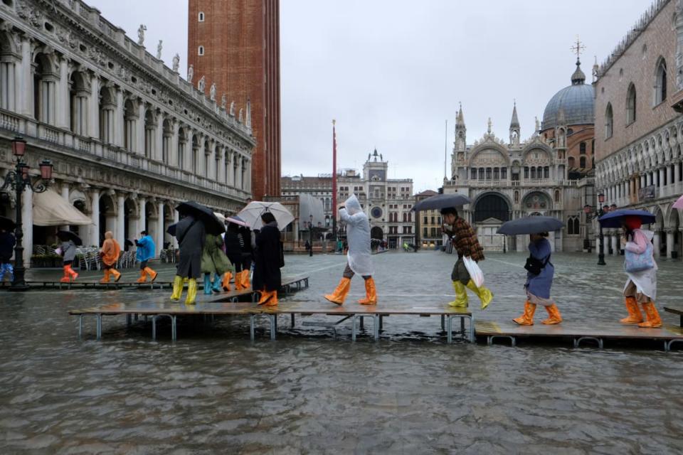 <div class="inline-image__caption"><p>Tourists and residents draped in waterproof clothing walk along raised sidewalks beside St. Mark’s Square. The area in front of the basilica floods around 100 times a year, but the water rarely inundates the entire city. </p></div> <div class="inline-image__credit">Manuel Silvestri/Reuters</div>