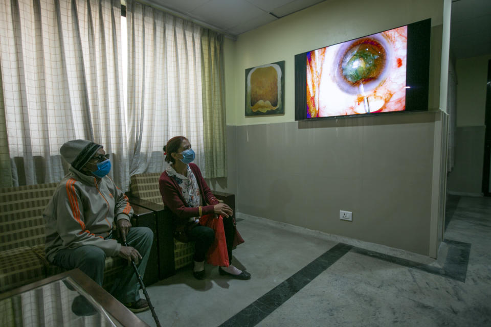An elderly Nepalese patient, left watches a live feed as Dr. Sanduk Ruit performs cataract surgery at the Tilganga Eye Center in Kathmandu, Nepal, March 26, 2021. Nepal’s “God of Sight” eye doctor renowned for his innovative and inexpensive cataract surgery for the poor is taking his work beyond the Himalayan mountains to other parts of the world so there is no more unnecessary blindness in the world. Ruit, who has won many awards for his work and performed some 130,000 cataract surgery in the past three decades, is aiming to expand his work beyond the borders of his home country and the region to go globally. (AP Photo/Niranjan Shrestha)