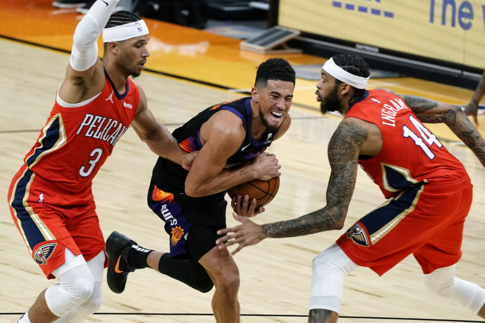 Phoenix Suns guard Devin Booker (1) runs down a loose ball between New Orleans Pelicans' Josh Hart and Brandon Ingram (14) during the second half of an NBA basketball game Tuesday, Dec. 29, 2020, in Phoenix. (AP Photo/Rick Scuteri)