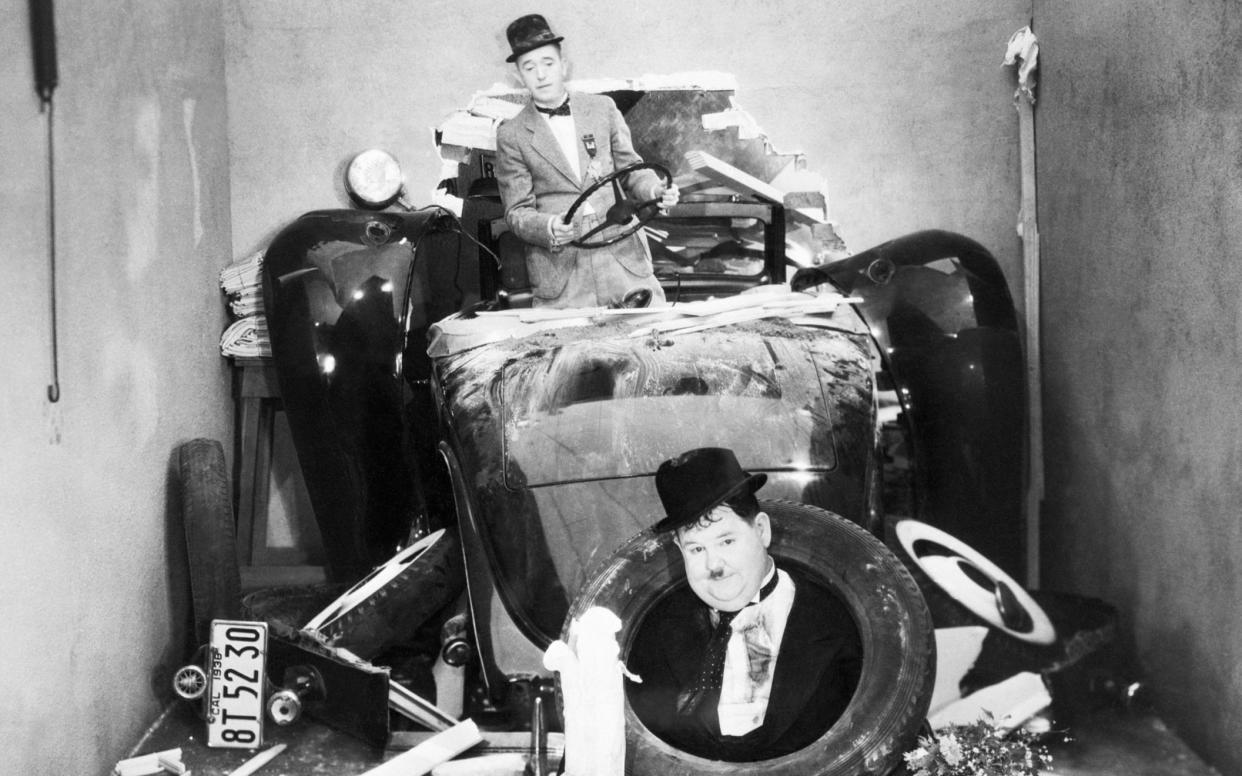 Stan Laurel and Oliver Hardy crashing through the wall in their automobile. Still from a 1938 movie