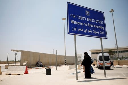 A Palestinian woman stands beneath a sign at the Israeli side of Erez crossing, on the border with Gaza