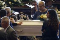 People stand by a small white coffin of a child ahead of a funeral service for some of the victims of a collapsed highway bridge, in Genoa's exhibition center Fiera di Genova, Italy, Saturday, Aug. 18, 2018. Saturday has been declared a national day of mourning in Italy and includes a state funeral at the industrial port city's fair grounds for those who plunged to their deaths as the 45-meter (150-foot) tall Morandi Bridge gave way Tuesday. (AP Photo/Gregorio Borgia)