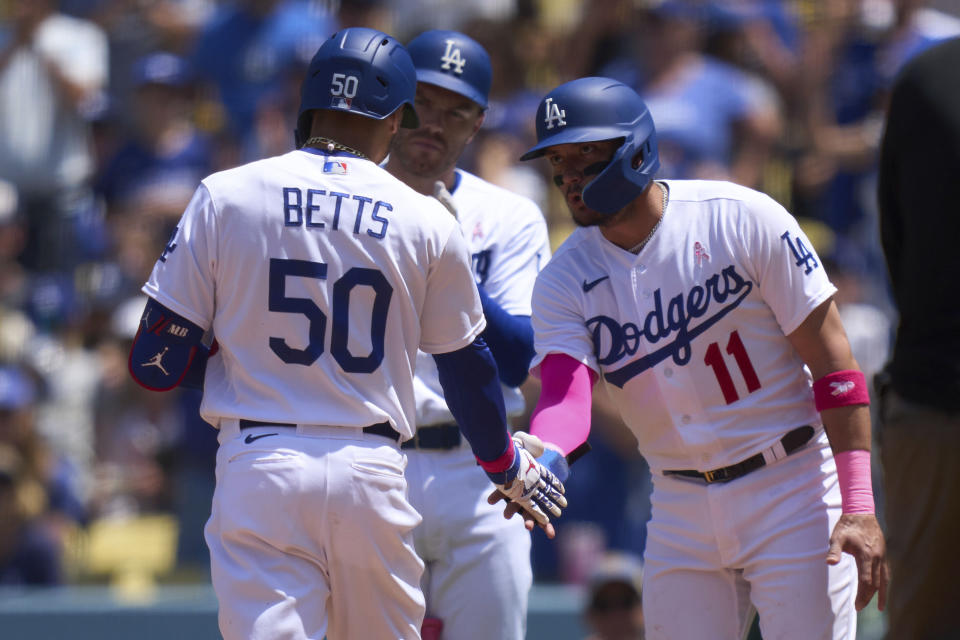 Los Angeles Dodgers' Mookie Betts (50) is congratulated by teammate Miguel Rojas (11) after hitting a home run on a fly ball to center field during the fourth inning of a baseball game against the San Diego Padres, Sunday, May 14, 2023, in Los Angeles. (AP Photo/Allison Dinner)