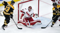 Carolina Hurricanes goaltender Frederik Andersen, center, gloves a save as Boston Bruins Charlie Coyle, left, and Patrice Bergeron, right, position for a drop during the second period of an NHL hockey game, Tuesday, Jan. 18, 2022, in Boston. (AP Photo/Charles Krupa)