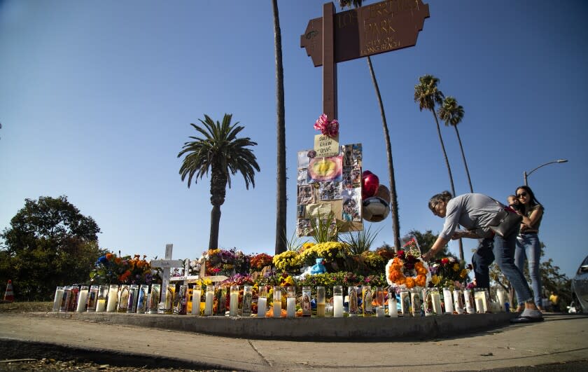 LONG BEACH, CA - NOVEMBER 3, 2019: Amy Garcia of Long Beach places a bouquet of flowers at a memorial near the scene where Jospeh Awaida, his son Omar and wife Raihan Dakhil were stuck by a DUI driver on Halloween night on November 3, 2019 in Long Beach, California. Awaida and his son were killed and Dakhil was critically injured.(Gina Ferazzi/Los AngelesTimes)