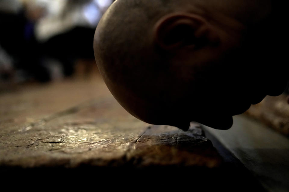 A Christian worshipper kisses the Stone of Unction, the stone slab traditionally claimed as the stone where Jesus' body was prepared for burial, in the Church of the Holy Sepulcher where many Christians believe Jesus was crucified, buried and rose from the dead, in the Old City of Jerusalem, on Good Friday, Friday, March 29, 2024. (AP Photo/Leo Correa)