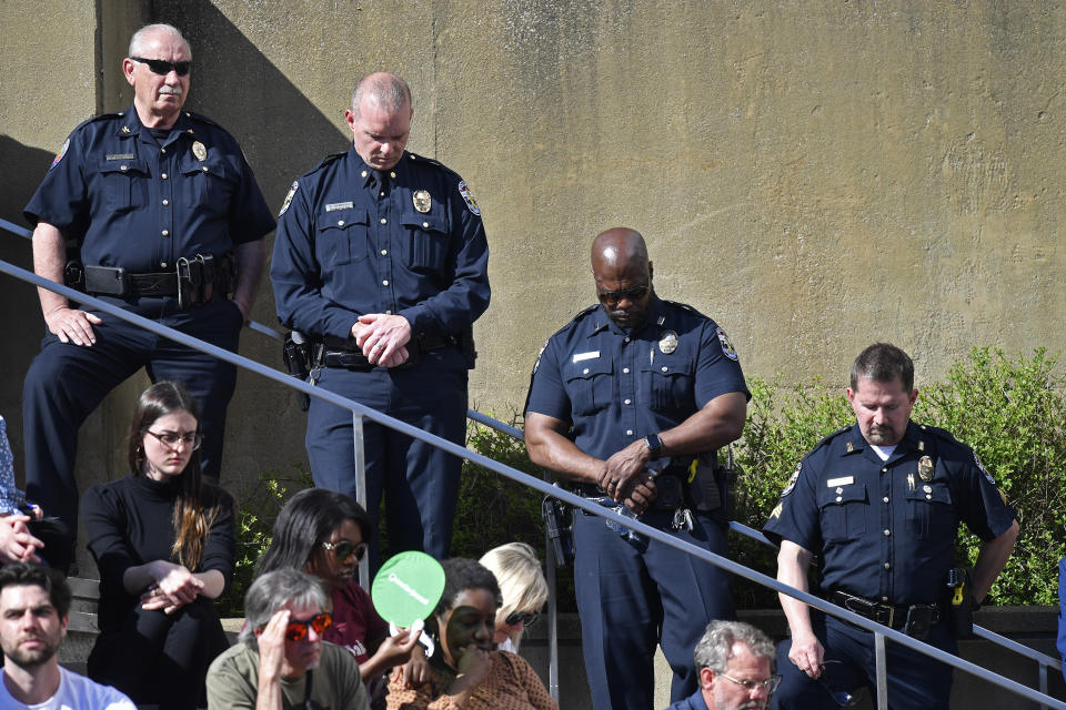 Officers with the Louisville Metro Police Department participate in a moment of silence during a vigil for the victims of Monday's shooting at the Old National Bank in Louisville, Ky., Wednesday, April 12, 2023. (AP Photo/Timothy D. Easley)