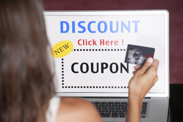 Natural beautiful woman using an online internet web coupon on her laptop paying with her Credit Card. Discount shopping Online.