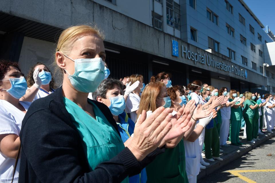 Healthcare workers dealing with the new coronavirus crisis applaud in return as they are cheered on by local police, Civil Guard and other security forces outside the University Hospital in Coruna, northwestern Spain, on March 26, 2020. - Spain's coronavirus death toll surged above 4,000 today but the increase in both fatalities and new infections slowed, leaving officials hopeful a nationwide lockdown is starting to curb the spread of the disease. A total of 655 deaths were recorded in the country in the last 24 hours, bringing the toll to 4,089, the health ministry said. (Photo by MIGUEL RIOPA / AFP) (Photo by MIGUEL RIOPA/AFP via Getty Images)