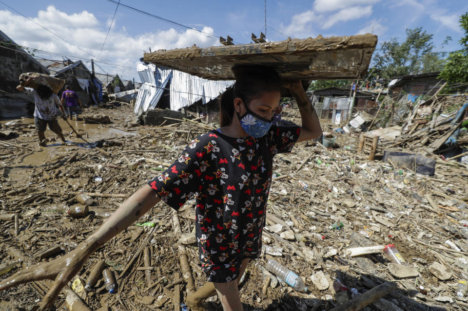 A resident carries a television across debris and floods at the typhoon-damaged Kasiglahan village in Rodriguez, Rizal province, Philippines on Friday, Nov. 13, 2020. Thick mud and debris coated many villages around the Philippine capital Friday after Typhoon Vamco caused extensive flooding that sent residents fleeing to their roofs and killing dozens of people. (AP Photo/Aaron Favila)