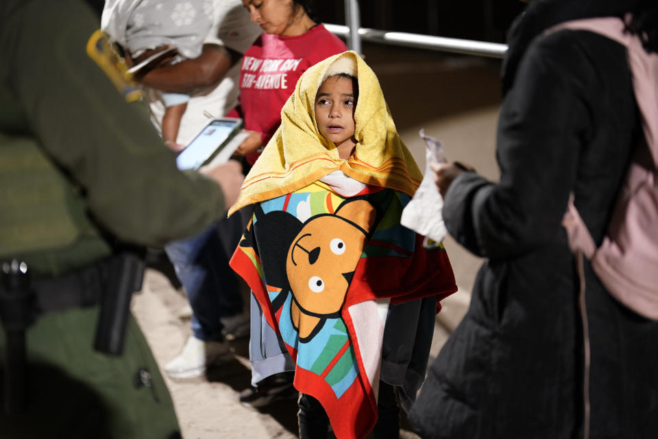 A girl and her mother answer questions as they wait to board a bus near Yuma, Arizona, Thursday, Nov. 3, 2022, after crossing the border from Mexico to the U.S. and surrendering to U.S. authorities to apply for asylum. (AP Photo/Gregory Bull)