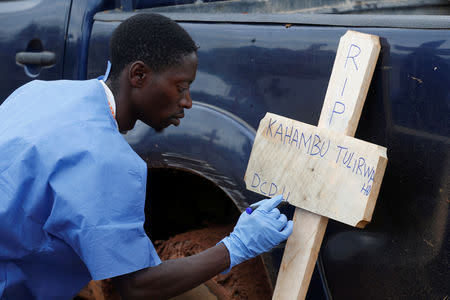 FILE PHOTO: A Congolese red cross worker writes on a cross the name of Congolese woman Kahambu Tulirwaho who died of Ebola, before a burial service at a cemetery in Butembo in the Democratic Republic of Congo, March 28, 2019. Picture taken March 28, 2019.REUTERS/Baz Ratner/File Photo