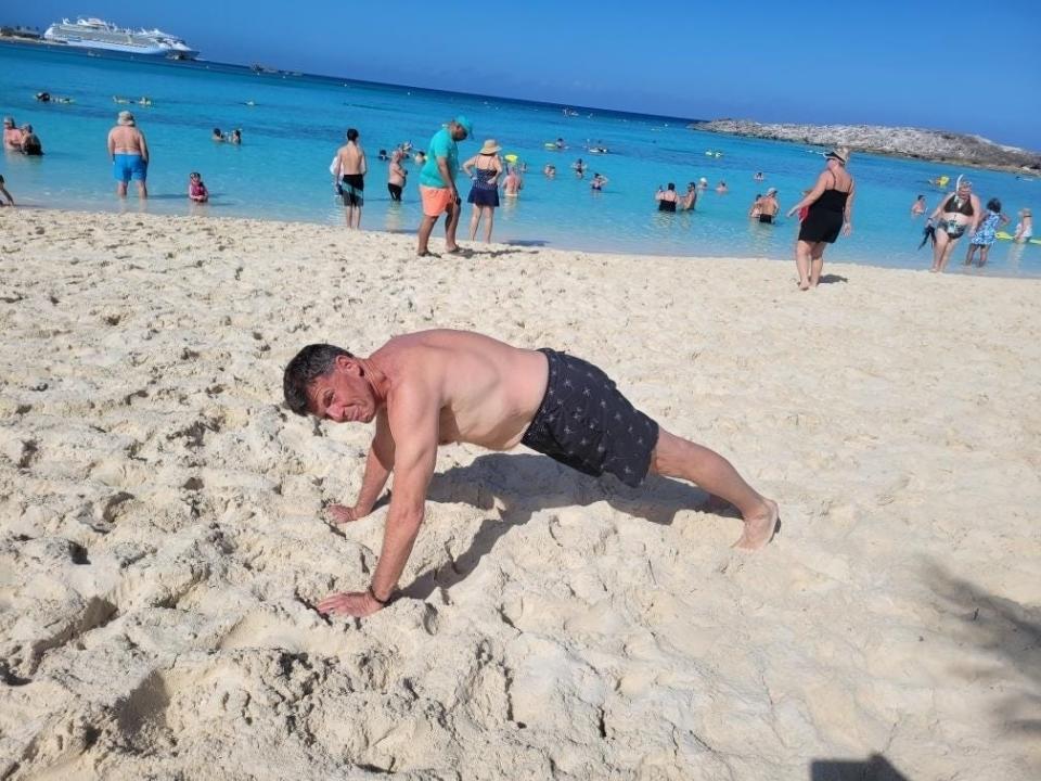 Everett Gooch wearing swim trunks and doing a push-up on a beach.