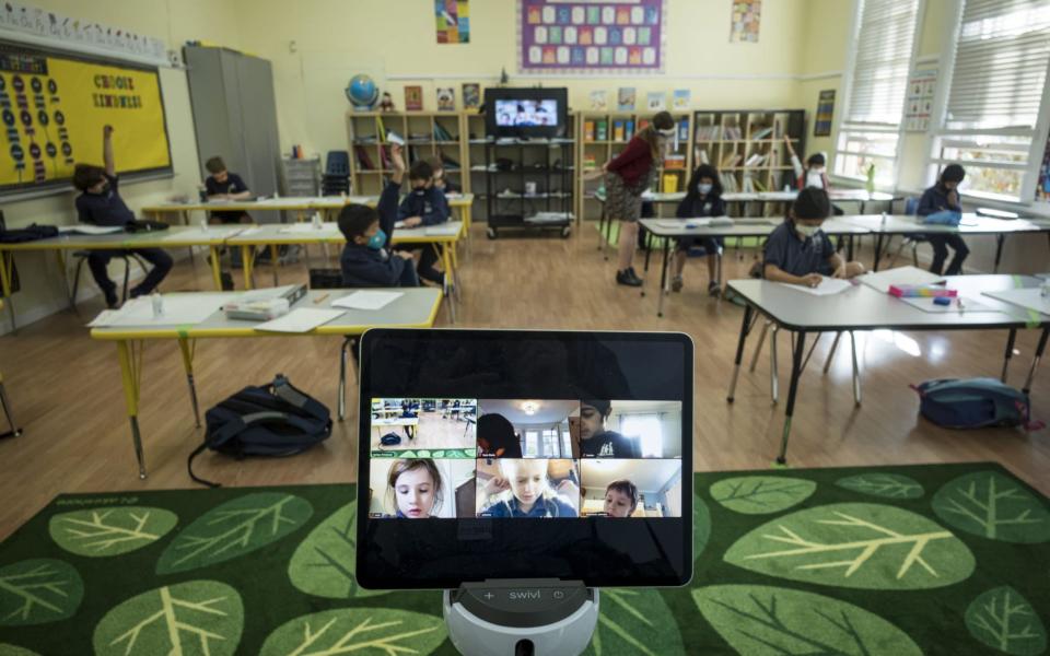 A monitor displays students learning remotely in a classroom at an elementary school - Bloomberg