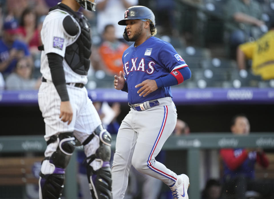 Texas Rangers' Willie Calhoun, right, scores on a single by Isiah Kiner-Falefa, next to Colorado Rockies catcher Dom Nunez during the third inning of a baseball game Wednesday, June 2, 2021, in Denver. (AP Photo/David Zalubowski)