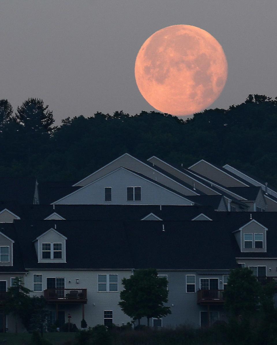 The Super Flower Blood Moon sets behind homes on a hill overlooking Carmel, N.Y. May 27, 2021. 