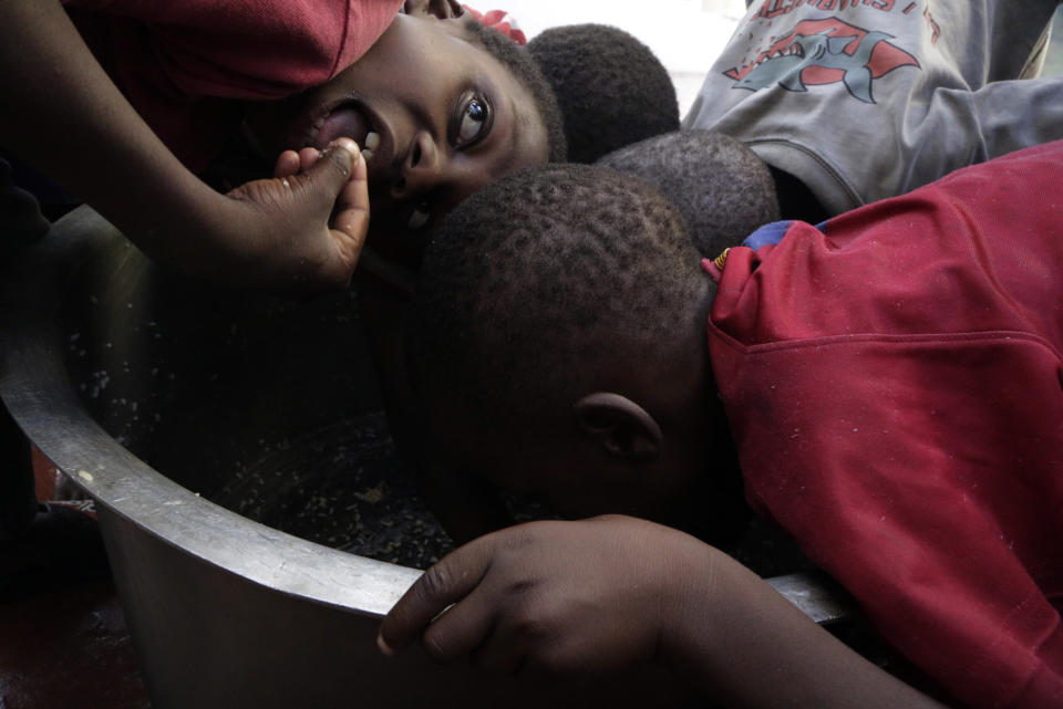 FILE - In this Friday, March 22, 2019 file photo, children scrape through for remaining rice inside a pot at a center for those displaced after Cyclone Idai hit coastal Mozambique, in Beira, Mozambique. These African stories captured the world's attention in 2019 - and look to influence events on the continent in 2020. (AP Photo/Themba Hadebe, File)