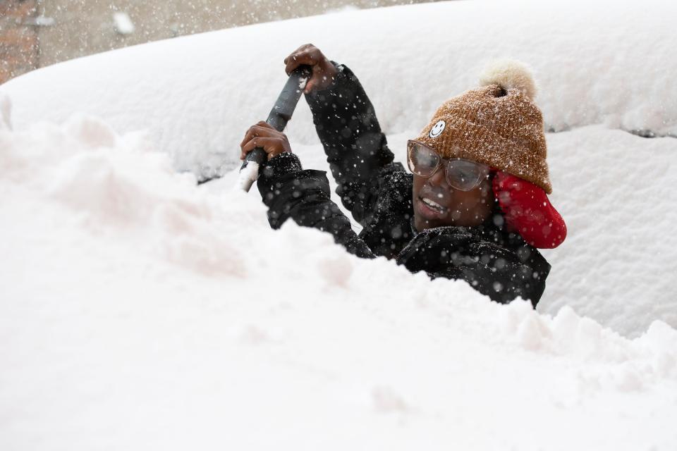 Zaria Black, 24, from Buffalo, clears off her car as snow falls Friday, Nov. 18, 2022, in Buffalo, N.Y.  A dangerous lake-effect snowstorm paralyzed parts of western and northern New York, with nearly 2 feet of snow already on the ground in some places and possibly much more on the way.  (AP Photo/Joshua Bessex)