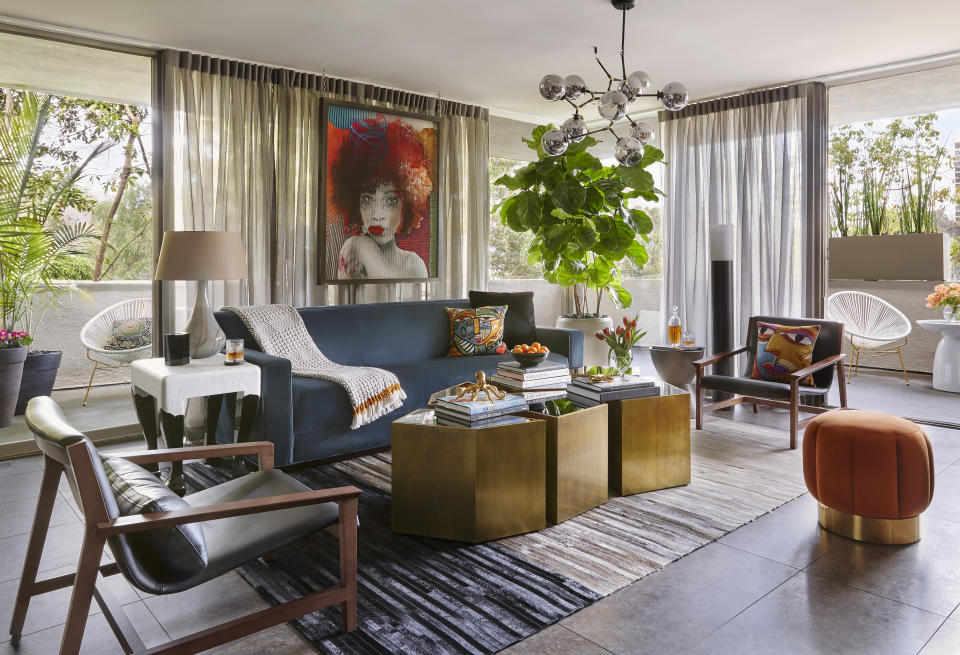 This image provided by Zeke Ruelas shows the living room of a residence with a blue velvet sofa. In John McClain's own Hollywood Hills home, this room is a neutral envelope for the blue velvet sofa. "I love that it adds vitality and color." To reflect the architecture, he chose a midcentury sofa style, "but the luxe blue velvet feels fresh and unexpected." (Zeke Ruelas via AP)