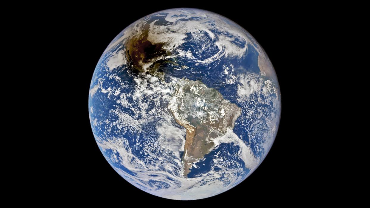 The planet Earth, as seen from the DSCOVR satellite. Earth appears as a bright blue dot against the darkness of space, with the shadow of an annular solar eclipse over much of North America.