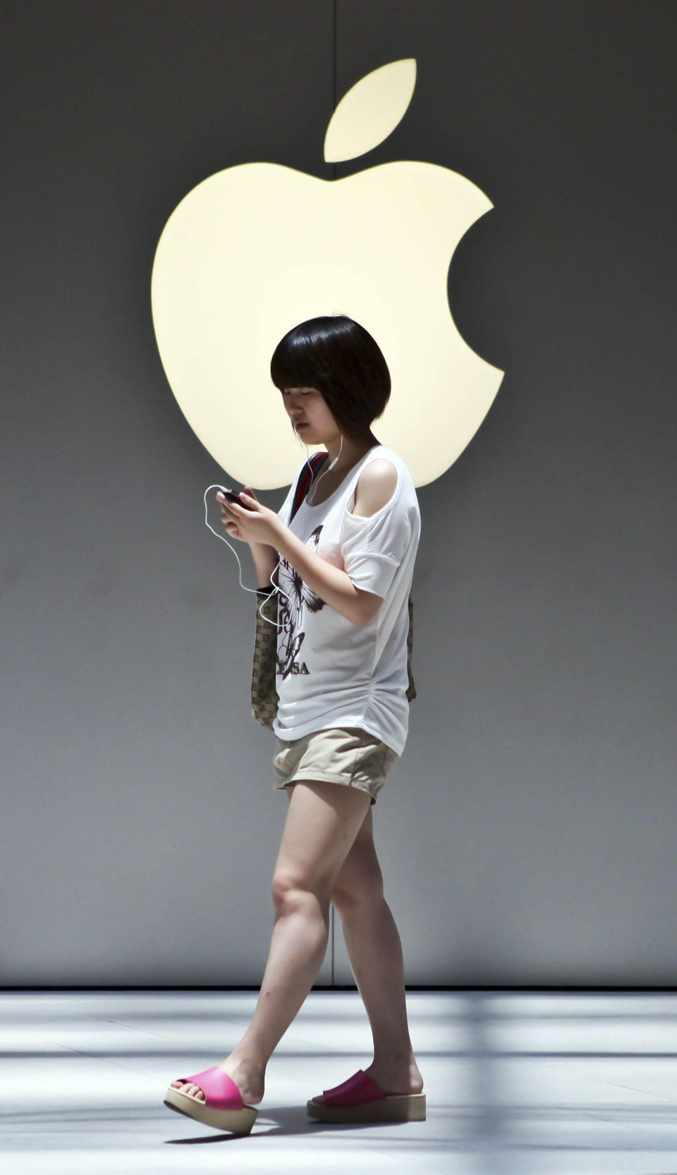 A woman walks near the Apple logo outside an Apple store in Shanghai, China on Monday July 2, 2012. Apple agreed to pay $60 million to settle a dispute in China over ownership of the iPad name, a court announced Monday, removing a potential obstacle to sales of the popular tablet computer in the key Chinese market. (AP Photo) CHINA OUT