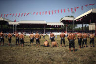 Wrestlers watch as others compete on the third and last day of the 660th instalment of the annual Historic Kirkpinar Oil Wrestling championship, in Edirne, northwestern Turkey, Sunday, July 11, 2021.Thousands of Turkish wrestling fans flocked to the country's Greek border province to watch the championship of the sport that dates to the 14th century, after last year's contest was cancelled due to the coronavirus pandemic. The festival, one of the world's oldest wrestling events, was listed as an intangible cultural heritage event by UNESCO in 2010. (AP Photo/Emrah Gurel)