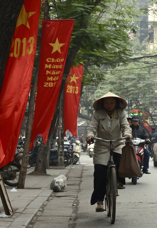 A cyclist rides past red banners marking the 2013 New Year in Hanoi on December 28, 2012. More than 25 years after it started a transition towards a market economy, the Vietnamese government is trying to unpick a web of state-owned firms, which have a stranglehold on the economy and are proving stubbornly resistant to reform