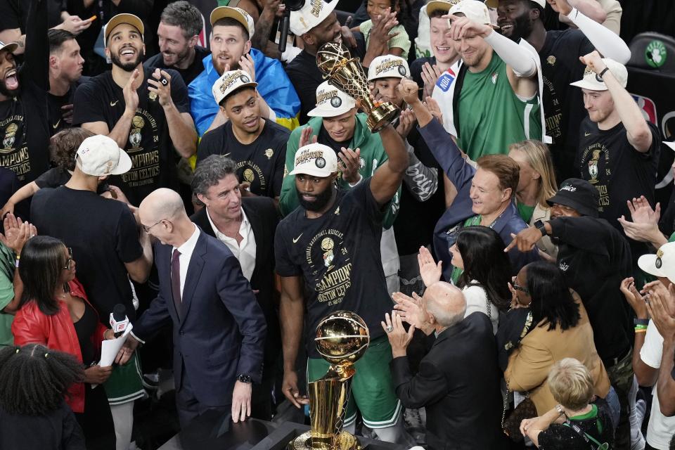 Boston Celtics' Jaylen Brown, center, raises the MVP trophy after defeating the Dallas Mavericks in Game 5 of the NBA basketball finals, Monday, June 17, 2024, in Boston. (AP Photo/Michael Dwyer)