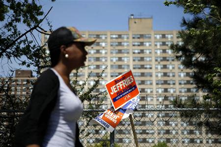 A woman walks next to a poster of Newark's mayoral candidate Shavar Jeffries during mayoral elections in Newark, New Jersey, May 13, 2014. REUTERS/Eduardo Munoz