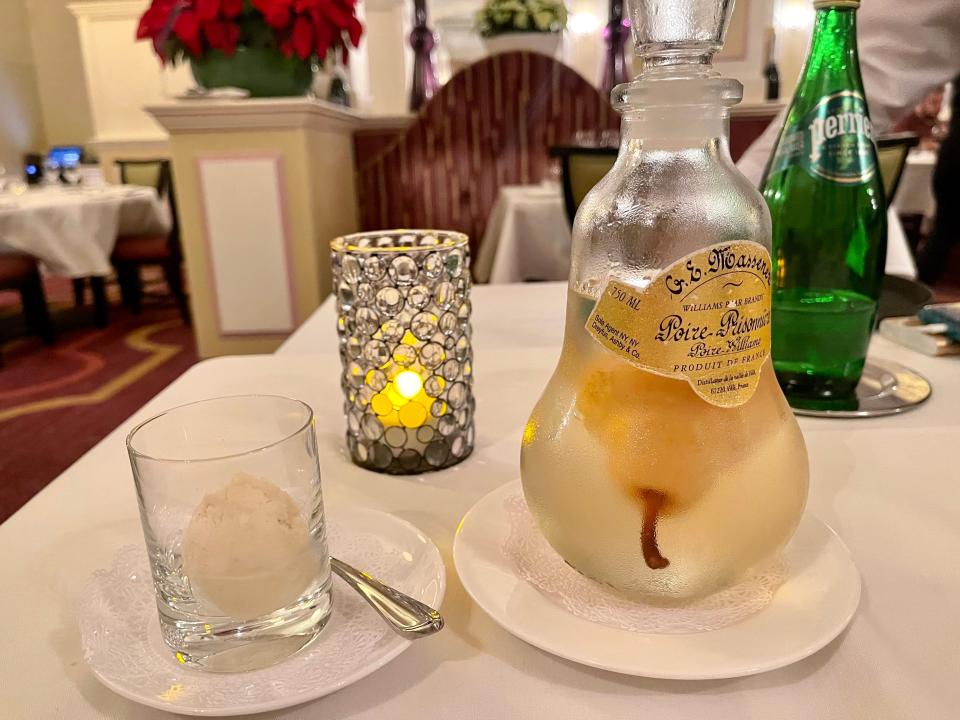 Cup of sorbet and large, glass container with pear brandy.