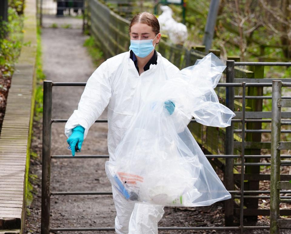 An officer removes bags of evidence from the scene