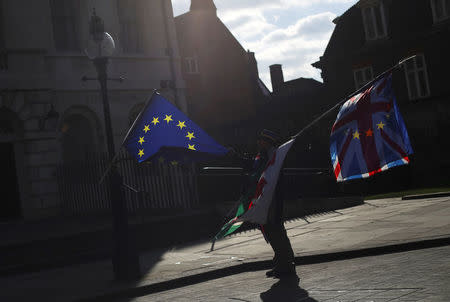 An anti-Brexit demonstrator waves EU, Union and Welsh flags opposite the Houses of Parliament in London, Britain, March 19, 2018. REUTERS/Hannah McKay