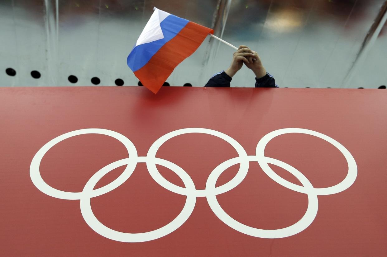 FILE - A Russian flag is held above the Olympic Rings at Adler Arena Skating Center during the Winter Olympics in Sochi, Russia on Feb. 18, 2014. The International Olympic Committee has made a sweeping move to isolate and condemn Russia over the country’s invasion of Ukraine. (AP Photo/David J. Phillip, File)