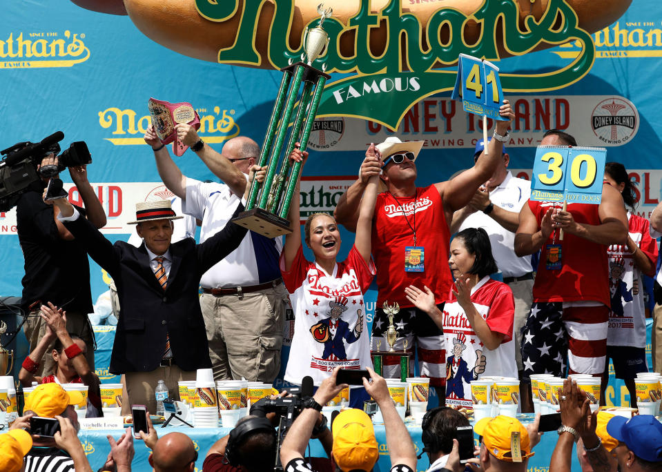 <p>US competitive eater Miki Sudo (C) raises the trophy after winning the Women’s Nathan’s Famous Fourth of July International Hot-dog eating contest in Coney Island, New York on July 4, 2017. Sudo won by consuming 41 hotdogs. (Peter Foley/EPA/Shutterstock) </p>