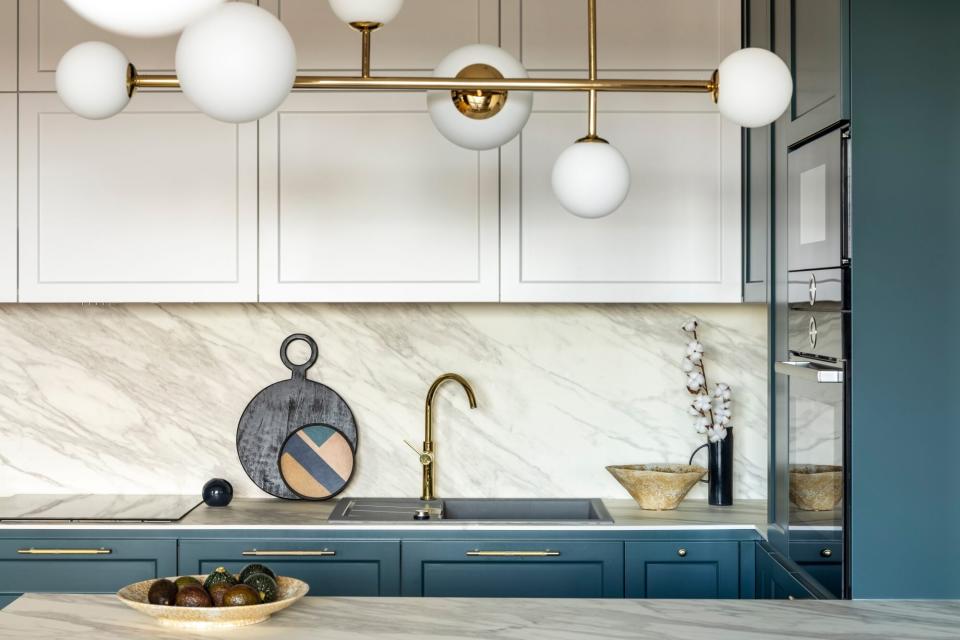 glam kitchen with marble backsplash and statement lighting