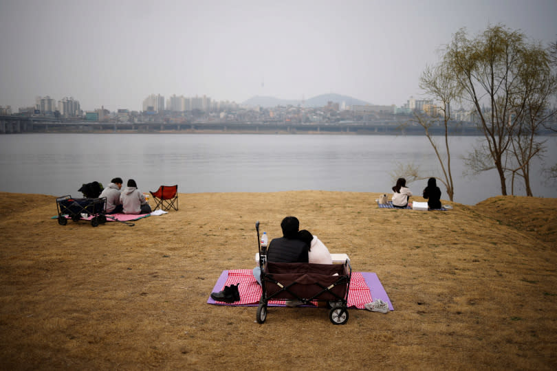 首爾民眾戴著口罩在漢江公園野餐（圖／路透社）