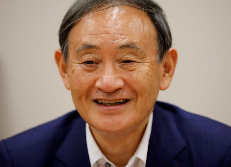 FILE PHOTO: Japan's top government spokesman Chief Cabinet Secretary Yoshihide Suga smiles during an interview with Reuters in Tokyo