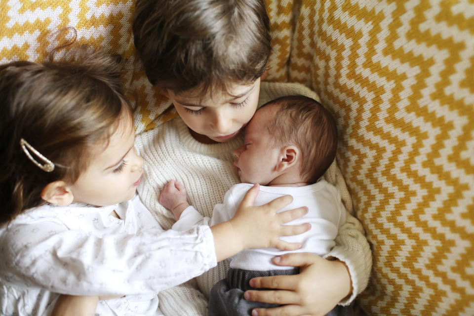 Sibling cradle their baby brother