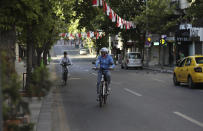 People ride bicycles on a deserted road during a lockdown, in Ankara, Turkey, Saturday, May 15, 2021. Turkey is in the final days of a full lockdown and the government has ordered people to stay home and businesses to close amid a huge surge in infections. But millions of workers are exempt and so are foreign tourists. (AP Photo/Burhan Ozbilici)