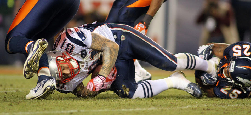 Chris Harris (25) of the Denver Broncos tackles Aaron Hernandez (81) of the New England Patriots on Dec. 18, 2011. After his death, Hernandez was found to have a degenerative brain disease that has been linked to head impacts. <cite>Marc Piscotty/Getty Images</cite>