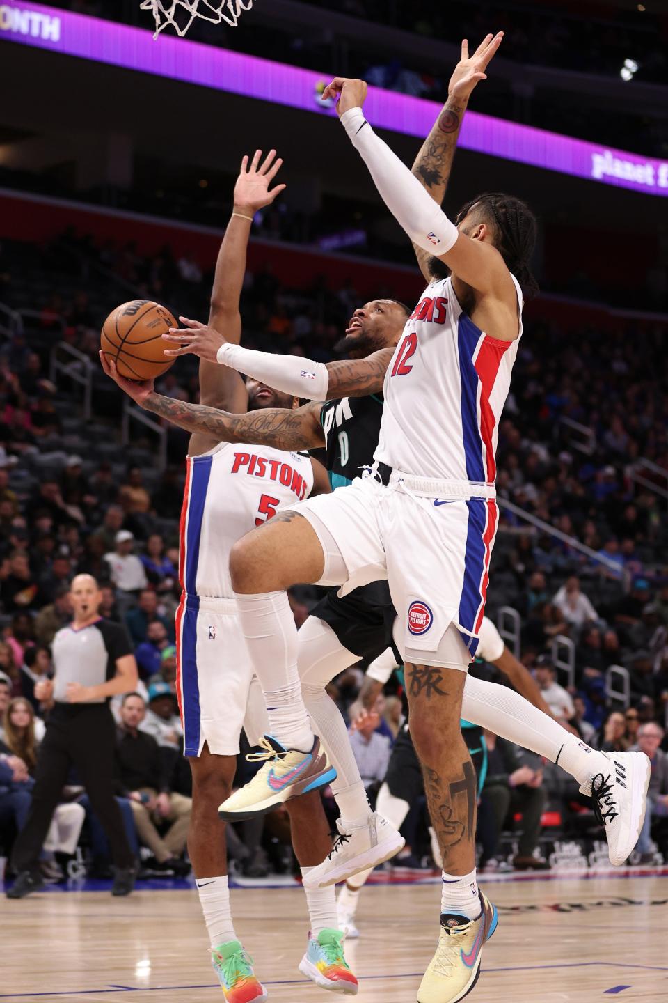 Trail Blazers guard Damian Lillard drives to the basket between the Pistons' Isaiah Livers, right, and Alec Burks during the first half on Monday, March 6, 2023, at Little Caesars Arena.