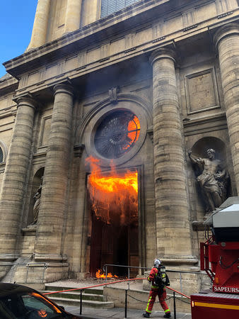 A member of the fire brigade reacts as Saint-Sulpice church is seen on fire in Paris, France, March 17, 2019 in this still image taken from social media obtained on March 18, 2019. INSTAGRAM @agneswebste/via REUTERS