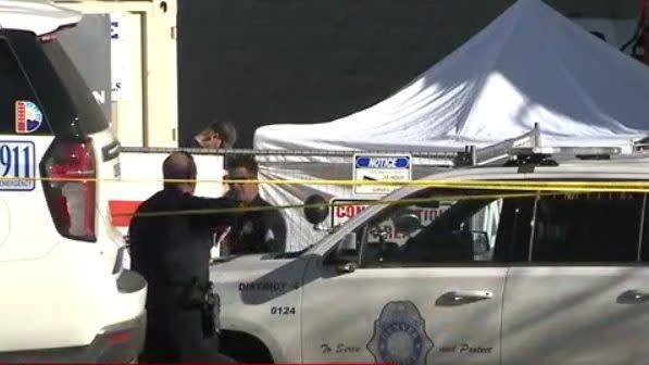 Crime scene tape, police vehicles in front of scene with large white tent
