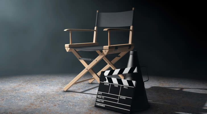A director's chair, megaphone and movie clapper are arranged in a dramatically lit room.