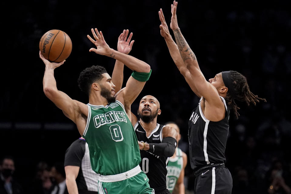 Boston Celtics forward Jayson Tatum (0) passes against Brooklyn Nets guard Patty Mills, right, during the first half of an NBA basketball game, Tuesday, Feb. 8, 2022, in New York. (AP Photo/John Minchillo)