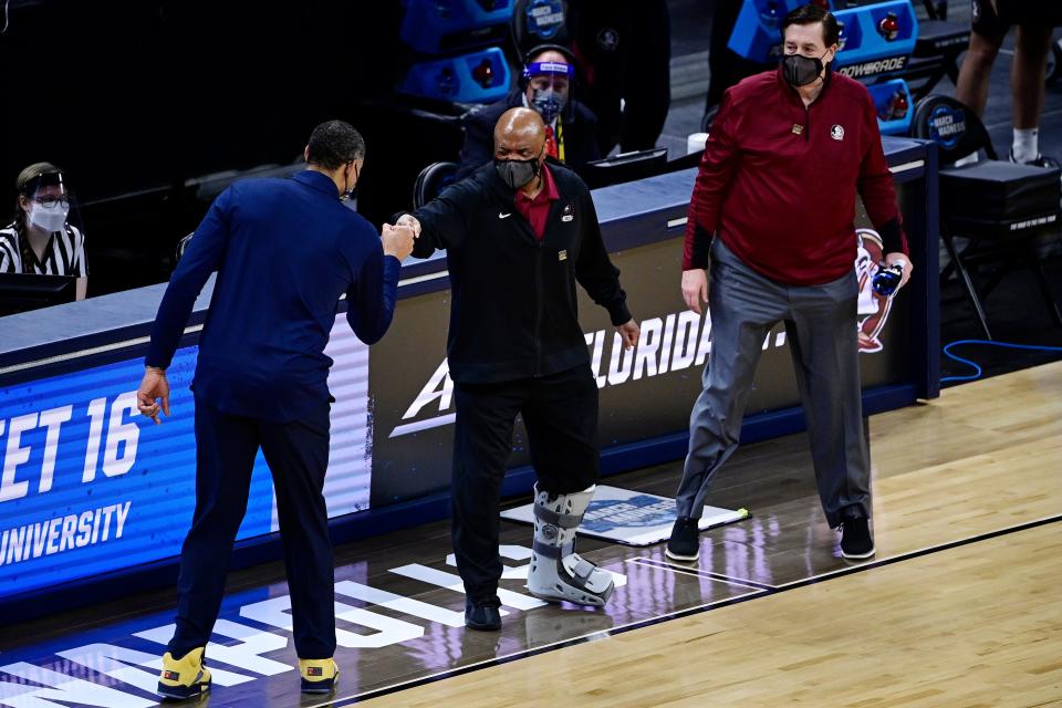 Florida State head coach Leonard Hamilton, center, fist bumps Michigan head coach Juwan Howard, left, following the Wolverines' victory in the Sweet 16.