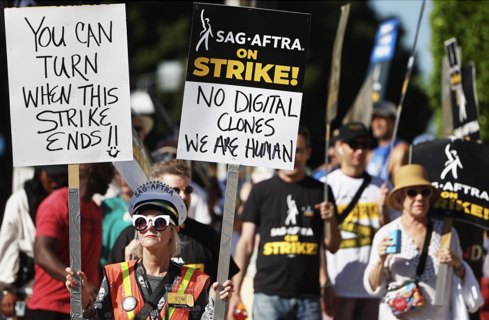 SAG AFTRA strikers with sign that says "no digital clones, we are human"