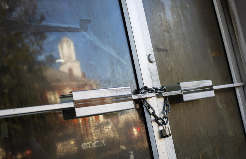 A shuttered storefront is padlocked as the Stewart County courthouse is reflected in the town square, Tuesday, Nov. 12, 2019, in Lumpkin, Ga. The town has few available resources, only three immigration lawyers work here full time. There are no hotels and many businesses in the downtown are shuttered. (AP Photo/David Goldman)