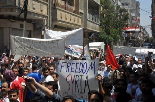 Syrian anti-government protesters hold banners as they march during a demonstration in Homs, June 2011. Security forces killed 11 civilians, including a mother and her daughter, most of them as they took part in massive protests across Syria calling for the fall of the regime, activists said